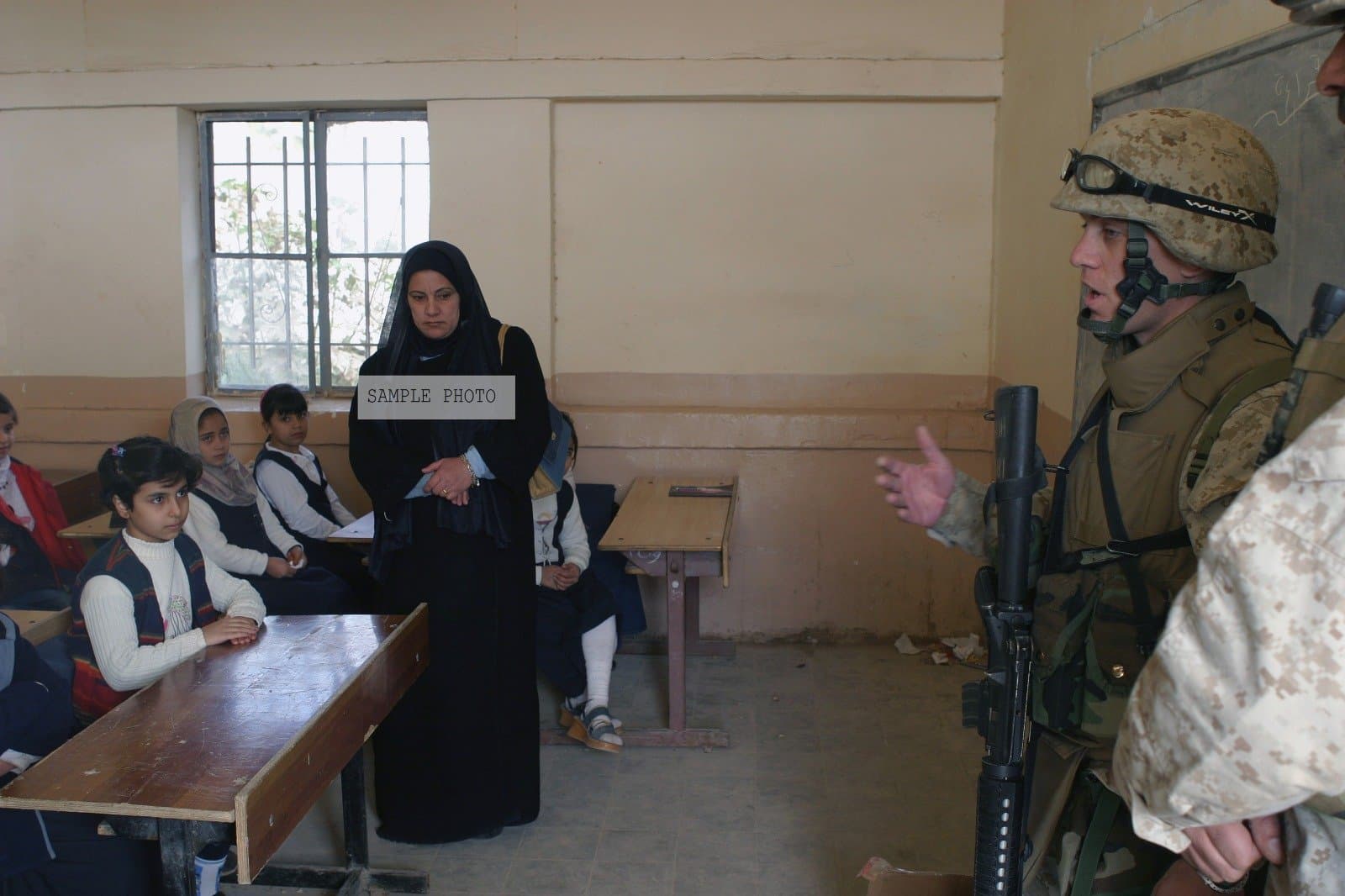 Photo U.S. Marine Corps CAPT. Christopher Perkins with the 2nd Battalion, 5th Marines, talks to Iraqi girls before distributing school supplies near the town of Ar Ramadi, Iraq during Operation Al Fajr, in support of Operation IRAQI FREEDOM on Dec. 11, 2004, 12/11/2004